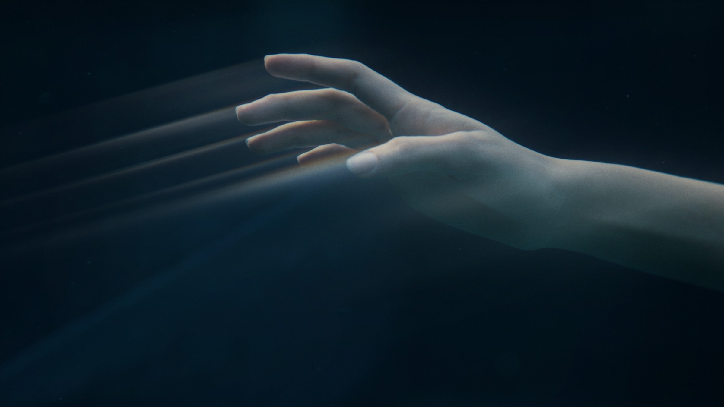 An outstretched hand underwater in near-darkness, with ShiftBox