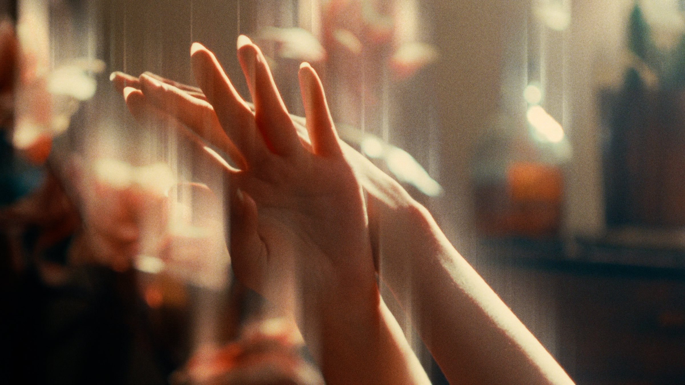 Two raised hands in warm light, flowers blurred behind, with ShiftBox